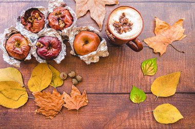 folyo fincan kahve ve ahşap arka plan üzerinde sonbahar yaprakları ile yedeklenmiş elma