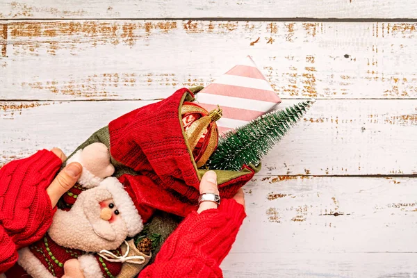 Woman hands holding Christmas stocking with gifts on white wooden background — Stock Photo, Image