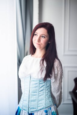 Gökyüzü mavisi korse ve beyaz gömlekli beyaz kadın tarihi balo dansına hazır.