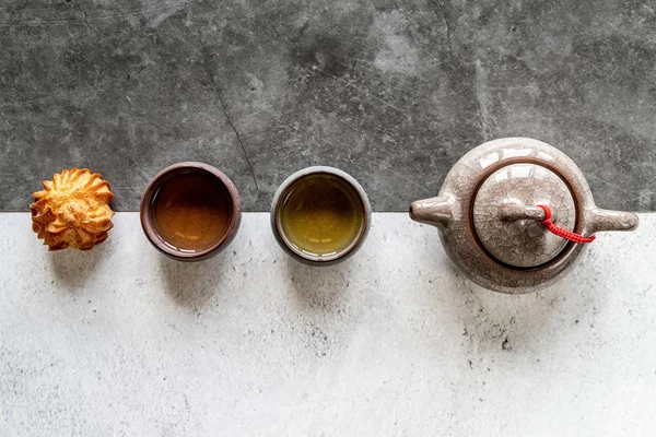 Asya çaydanlık, bardak ve beyaz ve siyah çift arka plan üst görünüm düz yatıyordu bir pasta