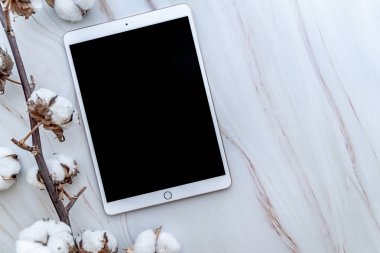 Mermer arka planda pamuk çiçekleri üst görünümü ile beyaz tablet