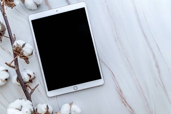 Mermer arka planda pamuk çiçekleri üst görünümü ile beyaz tablet