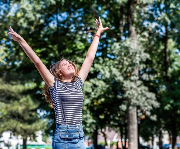 カジュアルな服を着た幸せな白人女性が笑顔で、夏の晴れた日に公園で楽しんでいます — ストック写真