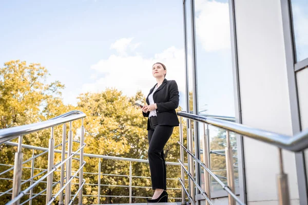 Beautiful caucasian business woman walking outdoors holding a digital tablet. City business woman working. — Stock Photo, Image