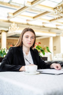 Kafede kahve içen belgelerle çalışan iş kadını