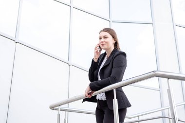 Güzel beyaz iş kadını açık havada yürürken cep telefonuyla konuşuyor. Şehir iş kadını çalışıyor.