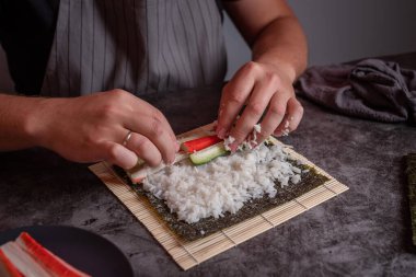 Gri önlüklü adam ev yapımı suşi pişiriyor.