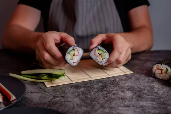 Человек в сером фартуке готовит домашние суши — стоковое фото