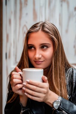 Lokantada hafif ışıkla kahve içen güzel bir kadın.