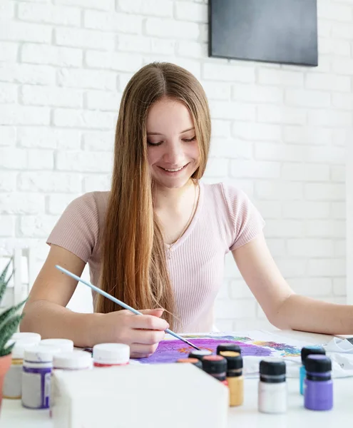 若い女性アーティストがスタジオで服に絵を描いているのを見て — ストック写真
