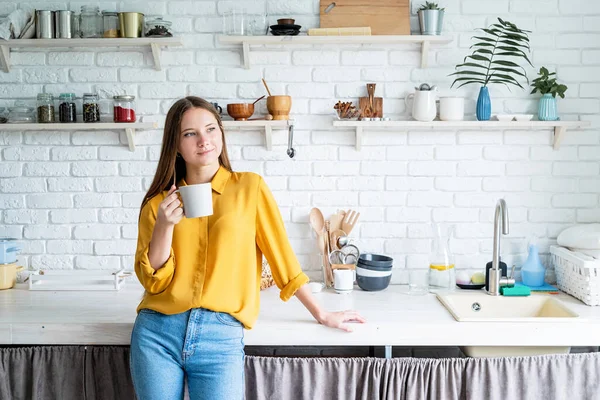 Genç ve çekici bir kadın mutfakta çay içiyor.