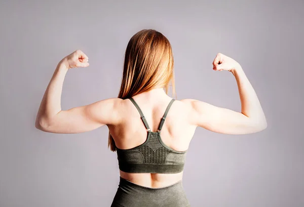 Спина і руки молодої спортивної м'язистої жінки ізольовані на сірому фоні — стокове фото