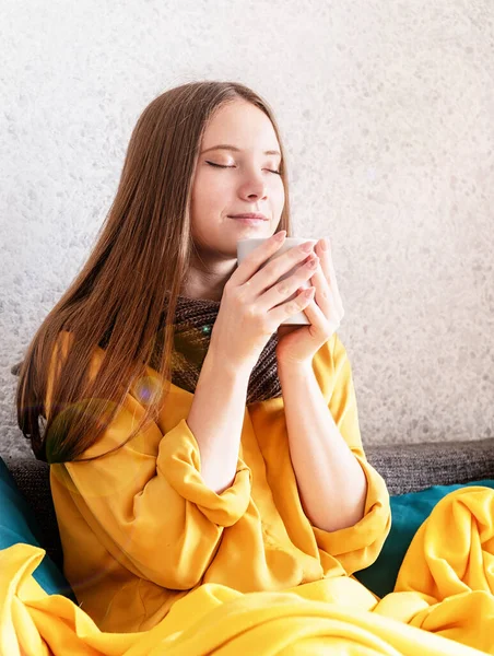 ソファに座ってコーヒーや紅茶を楽しむ女性 — ストック写真