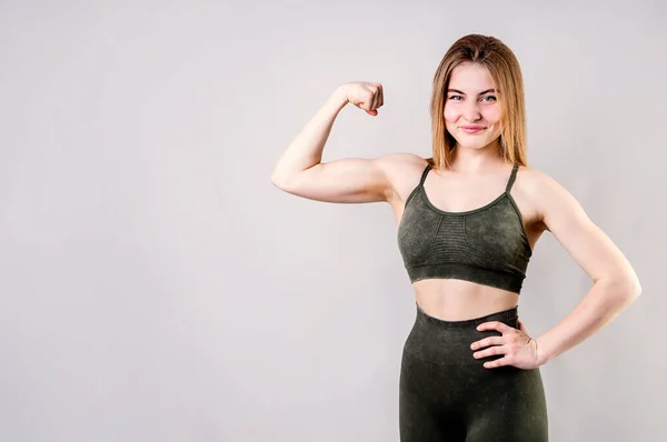 Sportos mosolygós nő bemutató bicepsz elszigetelt szürke háttér — Stock Fotó