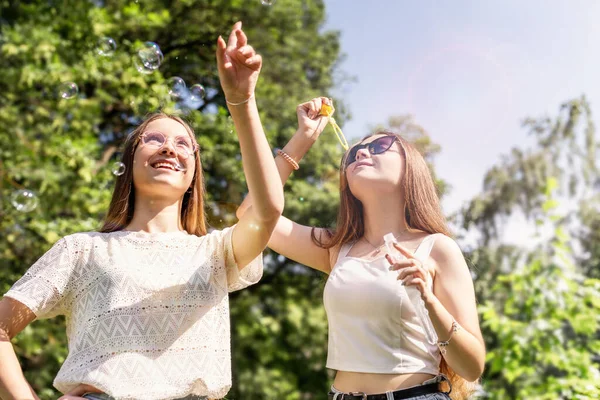 Duas meninas soprando bolhas de sabão e se divertindo juntos fora no dia de verão — Fotografia de Stock