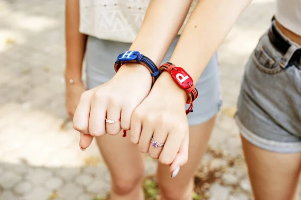 Duas amigas mostrando as mãos com pulseiras de amizade — Fotografia de Stock