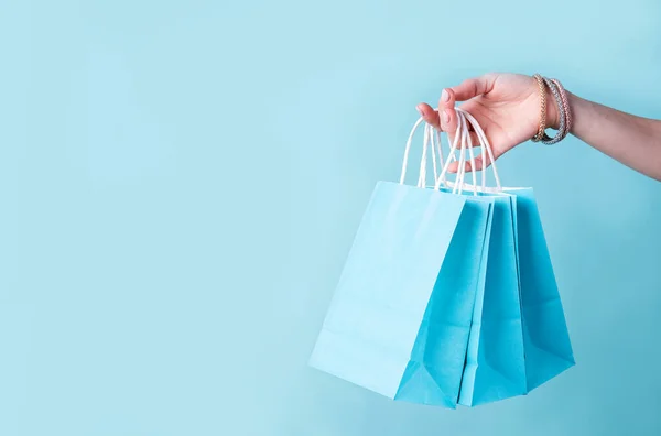 Frau Hand Trägt Ein Bündel Blauer Einkaufstüten Über Blauem Hintergrund — Stockfoto