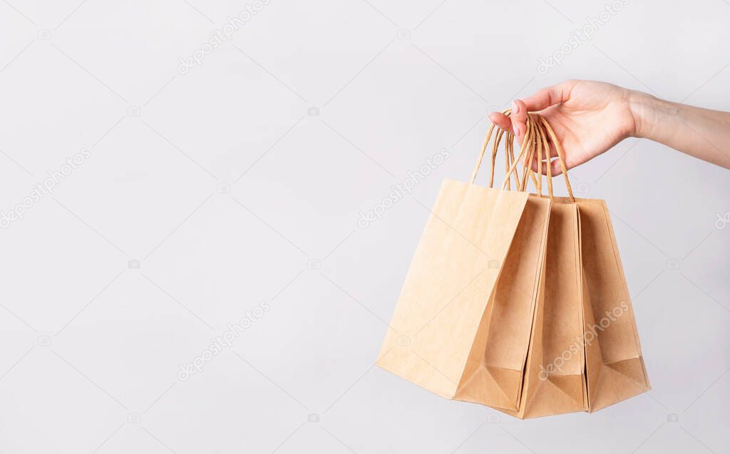 woman hand carrying a bunch of shopping bags over gray background with copy space
