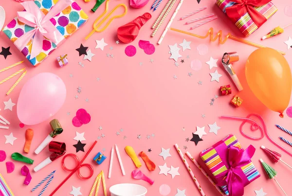 Birthday party background with party gifts, candles and balloons with copy space top view on pink background