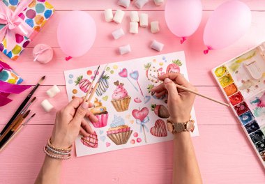 Yaratıcı sanatçı çalışma alanı. Kadın ellerinin pembe arka planda çizimlerinin üst görüntüsü