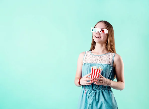 興奮したティーン女の子身に着けています3Dメガネ見て映画やポップコーンを食べます コピースペースと青の背景に隔離されました — ストック写真