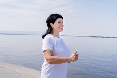 Aktif kıdemli kadın nehir kenarında koşuyor.