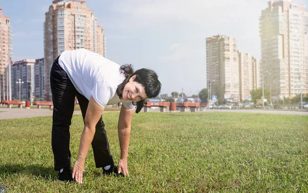 Sport and fitness. Senior sport. Active seniors. Smiling senior woman warming up stretching outdoors in the park