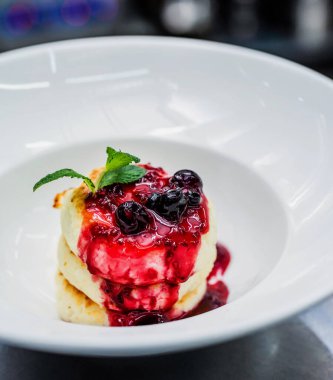 Tabağında taze böğürtlen ve nane olan süzme peynirli krep.