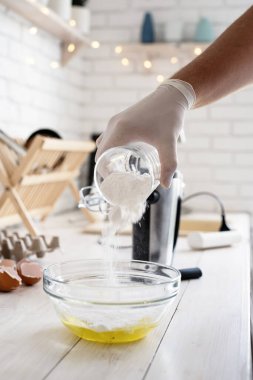 Noel yemeği ve pişirme. Barut şekerini cam yay ve beyaz ahşap masa üzerinde yumurtalar içine dök..