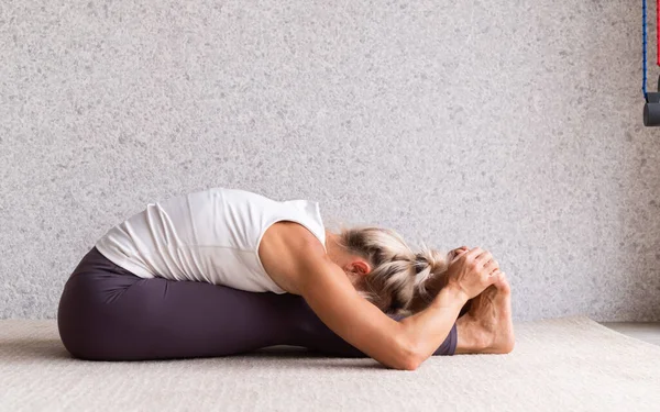 健康的生活方式年轻迷人的女子练习瑜伽 身穿运动服 白衬衫和紫色裤子 室内全长 灰色背景 — 图库照片