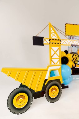 İnşaat temalı çocukların doğum günü partisi süslemesi oyuncak kazıcı kesimi, sarı, mavi ve siyah balonlar, güvenlik konileri, dikkat bandı ve şenlikli bir atmosfer yaratan neşeli aksesuarlar..