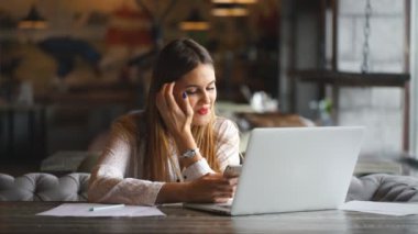 onu laptop yazarak işkadını gülümseyen ve bir akıllı telefon kullanır