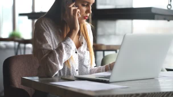 Geschäftsfrau arbeitet mit Laptop und telefoniert. — Stockvideo