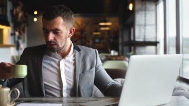 bir gri şık takım işleri pencerenin yakınındaki bir kafede bir dizüstü bilgisayar, bir genç işadamı