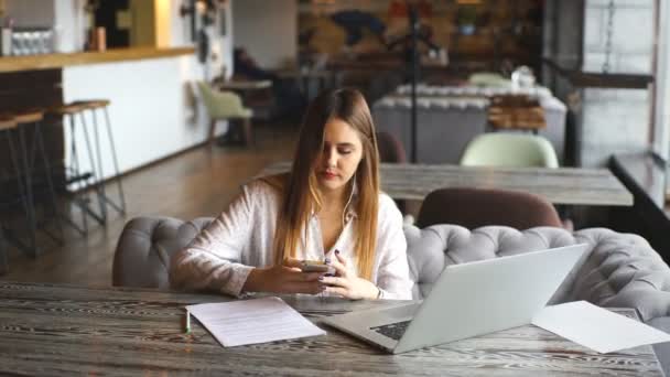 Belle femme d'affaires signe les documents et écouter de la musique sur les écouteurs — Video