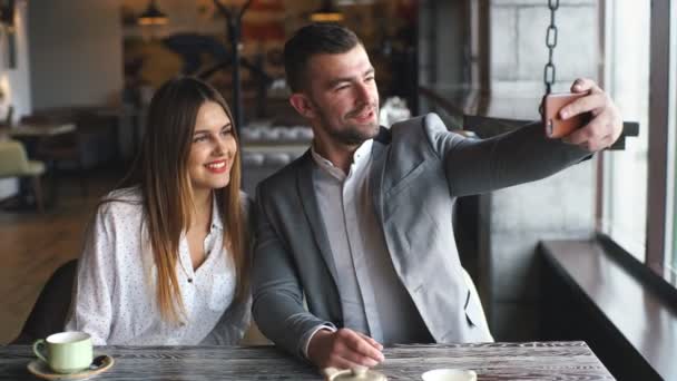 Conceito de tecnologia e pessoas - casal feliz tirando selfie com smartphone no shopping ou café — Vídeo de Stock