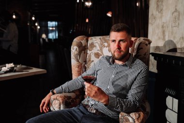 Genç bir adam pahalı bir restoran bir sandalyede oturan ve şarap içme