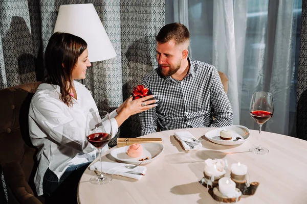 Una bella bruna fa un regalo al suo ragazzo in un ristorante ad un appuntamento — Foto Stock