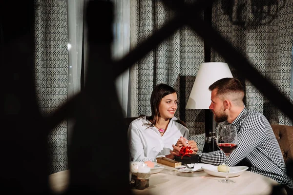 El hombre le dio a su novia un regalo para el día de San Valentín y sostiene sus manos — Foto de Stock