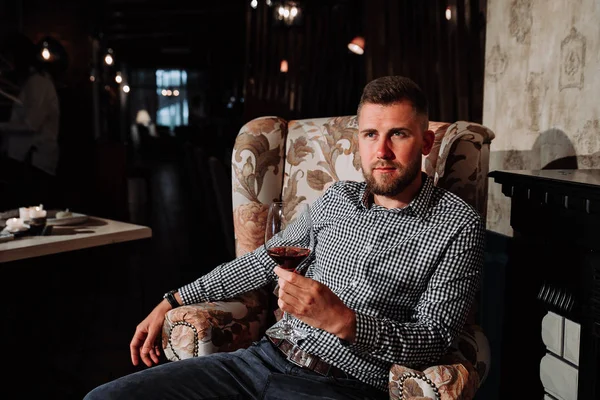 Genç bir adam pahalı bir restoran bir sandalyede oturan ve şarap içme