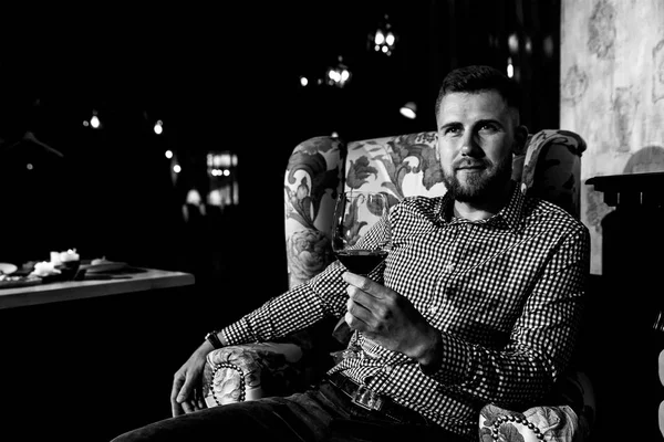 Genç bir adam pahalı bir restoran bir sandalyede oturan ve şarap içme