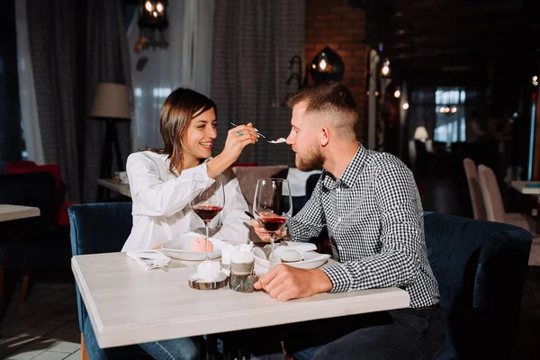 Young couple feeding each other in restaurant — Stock Photo, Image