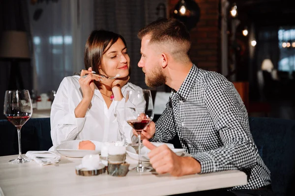 Girl feeds her boyfriend in a restaurant delicious dessert — Stock Photo, Image
