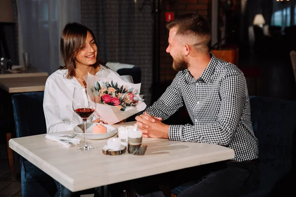 Attraktiv ung kvinna att få en blommor från hennes pojkvän medan du sitter i caféet — Stockfoto