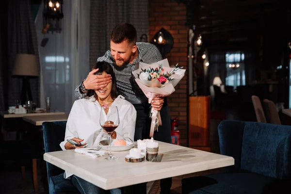 Attrayant jeune femme obtenir des fleurs de son petit ami tout en étant assis dans le café — Photo