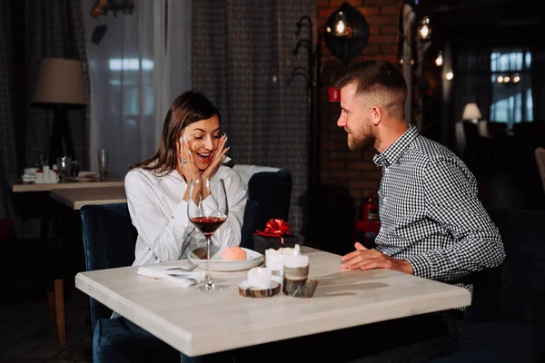 Portrait of happy and surprised young woman receiving present from boyfriend while sitting in cafe — Stock Photo, Image