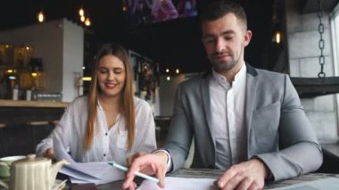 İşkadını kafede toplantı sırasında onun meslektaşım söz kağıtları ile gülüyor