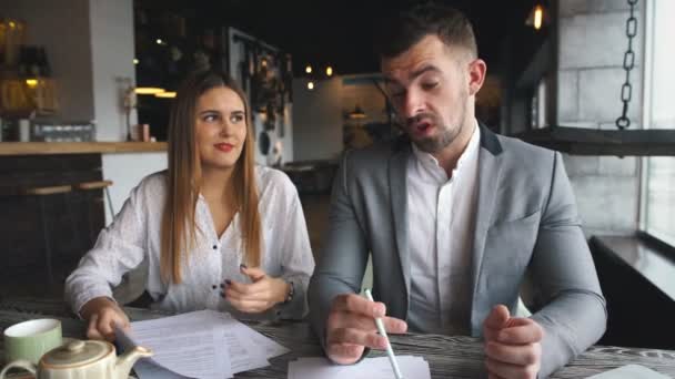 Jeune homme et femme d'affaires assis dans un café et discuter contrat — Video