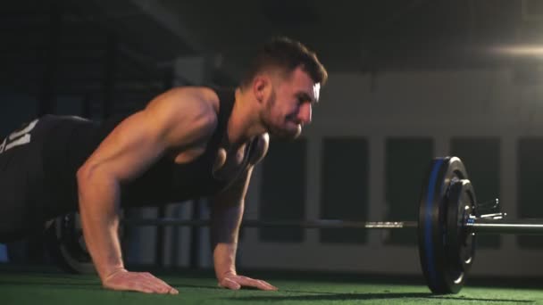 Aardige kerel met een baard zich voorbereidt op een pushup in de sportschool op een zwarte achtergrond maken — Stockvideo