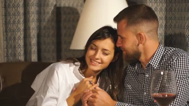 Casal apaixonado sentado em uma cadeira, abraçar uns aos outros e beber videira em um café ou restaurante . — Vídeo de Stock